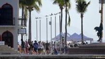 Tourists walk on the boardwalk of Puerto Vallarta, Jalisco state, Mexico on February 24, 2026. Known as a sunny tourist paradise, parts of the coastal city of Puerto Vallarta seem more like the set of a war film in the aftermath of violent chaos spurred by the capture and death of Mexico's most-wanted drug lord Nemesio "El Mencho" Oseguera. (Photo by Alfredo ESTRELLA / AFP via Getty Images)