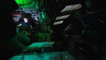 Astronaut Christina Koch is illuminated by a screen inside the darkened Orion spacecraft on the third day of the agency's Artemis II mission.