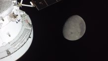 The sunlit Orion spacecraft near the moon. The Orientale basin, a 600-mile-wide, mountain-ringed crater, sits on the moon's lower half.